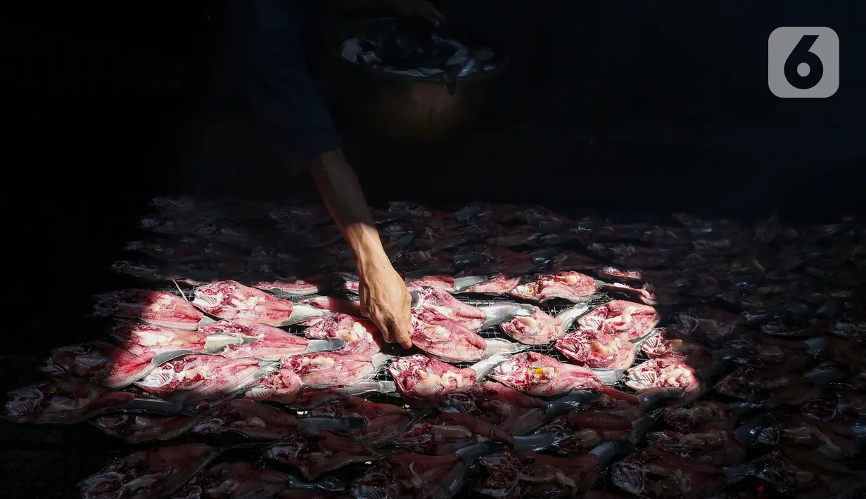 Pekerja melakukan pengasapan lele menggunakan kayu bakar di Desa Pengasinan, Gunung Sindur, Bogor, Rabu (30/9/2020). Pengasapan lele milik Haji Sueb yang berdiri sejak tahun 1998 dijual Rp 100.000 per kg yang berisi sekitar 25 ekor. (Liputan6.com/Fery Pradolo)