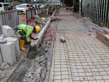 Pekerja menggarap proyek penataan jalur pedestrian di Jalan Gatot Subroto, Jakarta, Selasa (13/3). Penataan ini bertujuan untuk memberi kenyamanan dan keamanan bagi pejalan kaki. (Liputan6.com/Arya Manggala)