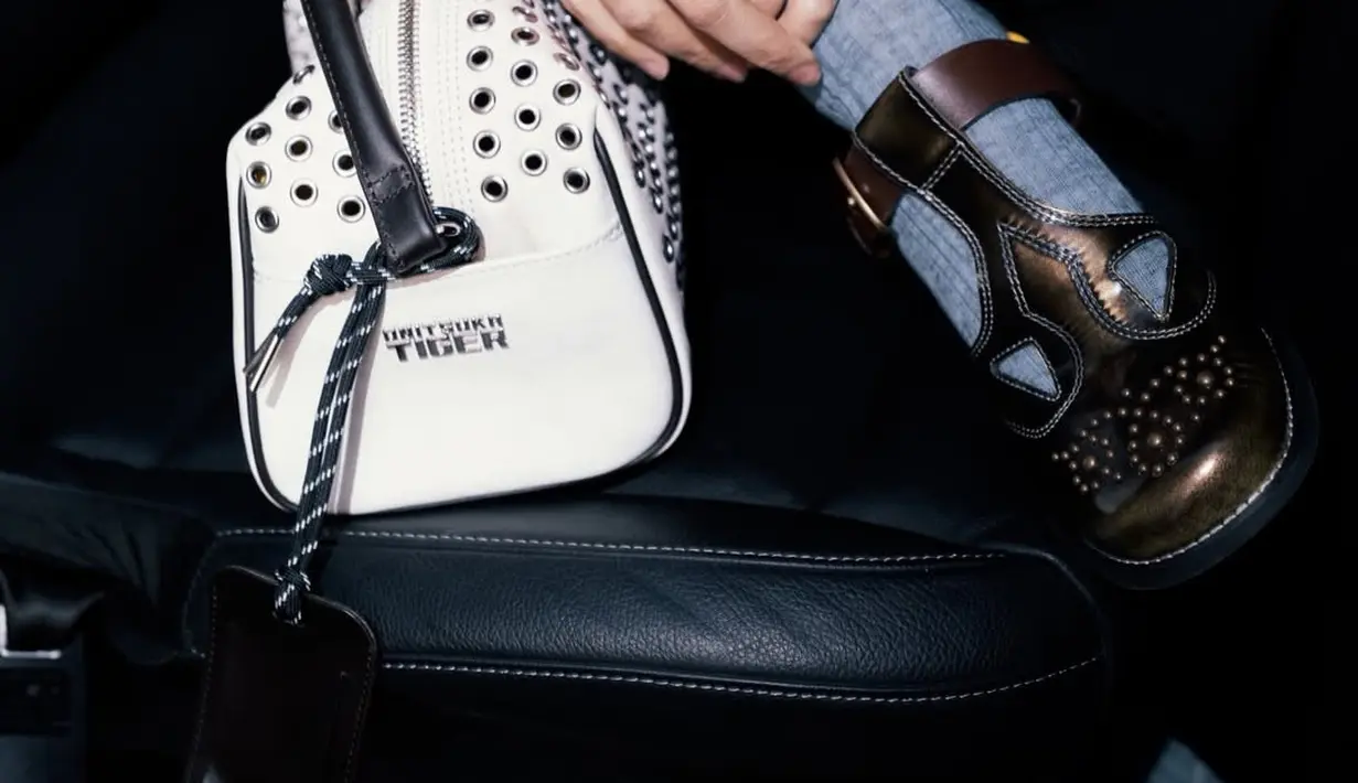 Aksesori utama yang menjadi sorotan adalah tas tangan putih dengan detail perforasi dan aksen metal yang merupakan koleksi Autumn Winter 2026 Onitsuka Tiger. Desainnya terasa futuristik namun tetap wearable, memperkuat karakter smart urban yang ingin ditampilkan. Tambahan luggage tag hitam memberi sentuhan travel aesthetic yang relevan dengan suasana Milan Fashion Week.  [@raisa6690].
