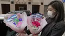 Pemilik toko bunga Iris Leung memberikan bunga dengan masker kepada pembeli pada Hari Valentine di Hong Kong, Jumat (14/2/2020). China  melaporkan peningkatan tajam dalam jumlah orang yang terinfeksi virus baru, ketika jumlah korban mendekati 1.400. (AP Photo/Vincent Yu)