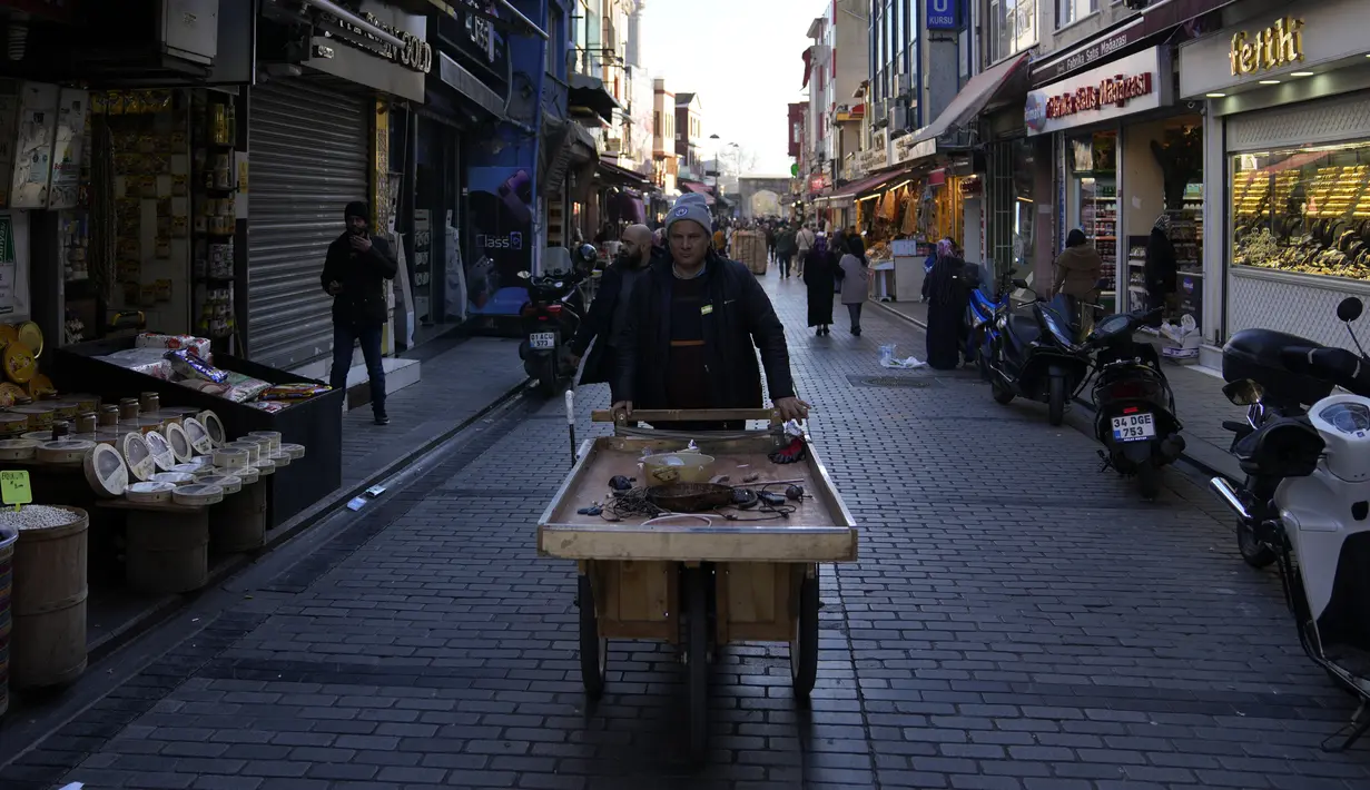 Seorang pedagang kaki lima mendorong gerobak roda di pasar di distrik Fatih Istanbul, Turki, Selasa, 3 Januari 2023. Presiden Recep Tayyip Erdogan  yang menghadapi pemilihan pada Juni mendatang, telah menjanjikan penurunan tingkat inflasi di tahun baru 2023. (AP Photo/Khalil Hamra)