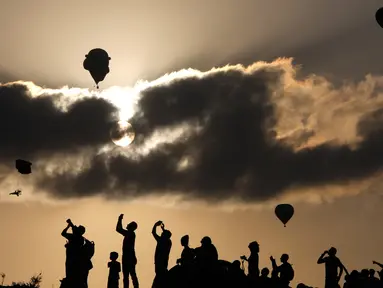 Pengunjung menyaksikan Festival Balon Udara Gilboa di dekat Kibbutz Ein Harod, Lembah Jizreel, Israel (4/8). Acara ini juga dimeriahkan dengan pertunjukan paragliders, paramotor dan karya para seniman udara. (AFP Photo/Manahem Kahana)