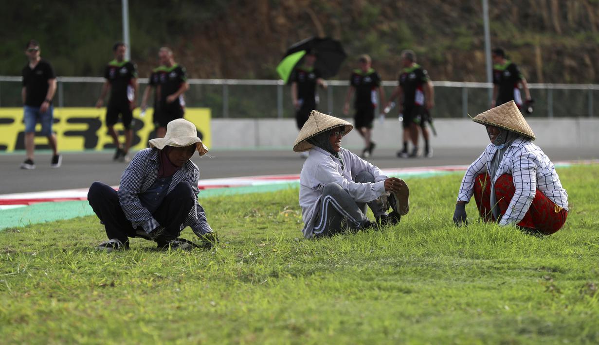 Namun dibalik semua itu ada beberapa visual yang menari untu disimak. Salah satunya  kebahagian warga lokal yang sedang merapihkan rumput di area Sirkuit Internasional Mandalika agar terlihat lebih indah dan asri. (AP Photo/Achmad Ibrahim)