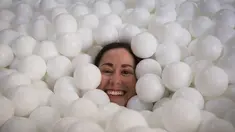 Seorang wanita tersenyum saat tenggelam dalam kolam bola putih di kantor SoHo, New York City, Selasa (25/8/2015). Tempat ini dibuat agar para karyawan dapat bermain dan dapat menhasilkan sesuatu yang kreatif. (REUTERS/Mike Segar)