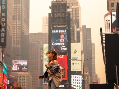 Seorang pejalan kaki berpose untuk berfoto di Times Square di tengah kabut asap dari kebakaran hutan dari Kanada, di New York City, Rabu (7/6/2023). (David Dee Delgado/Getty Images/AFP)