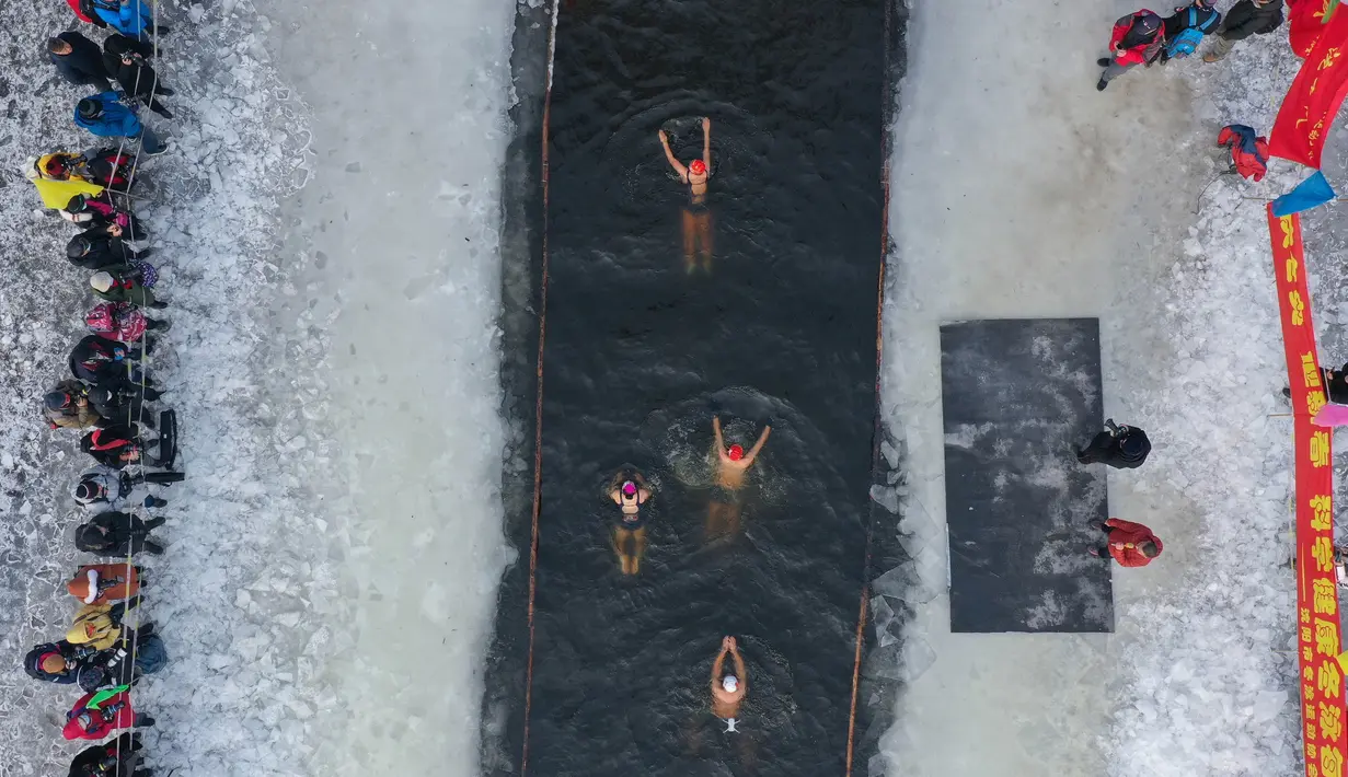 Foto udara pada 25 Januari 2022 menunjukkan penggemar renang musim dingin berenang di danau yang sebagian beku di Shenyang, di provinsi Liaoning, China. Penduduk lokal banyak menggemari kebiasaan berenang di musim dingin di mana banyak sungai dan danau-danau mulai membeku. (STR/AFP)