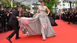Seorang asisten membantu merapikan gaun panjang aktris blasteran Inggris-Thai, Araya A. Hargate saat tiba di karpet merah pemutaran film "The BFG" (Le Bon Gros Geant) pada Festival Film Cannes ke-69 di Cannes, Prancis, Sabtu (14/5). (Loic VENANCE/AFP)
