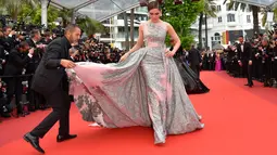 Seorang asisten membantu merapikan gaun panjang aktris blasteran Inggris-Thai, Araya A. Hargate saat tiba di karpet merah pemutaran film "The BFG" (Le Bon Gros Geant) pada Festival Film Cannes ke-69 di Cannes, Prancis, Sabtu (14/5). (Loic VENANCE/AFP)