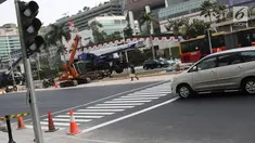 Sebuah mobil melintasi jalur khusus penyeberangan orang atau Pelican Crossing di kawasan MH Thamrin, Jakarta, Minggu (29/7). Pemasangan pelican crossing ini sebagai pengganti JPO di Bundaran HI yang akan dirobohkan. (Liputan6.cpm/Herman Zakharia)