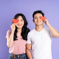 Sepasang kekasih memegang kertas berbentuk hati berwarna merah (Foto Dok: Freepik/1112000).