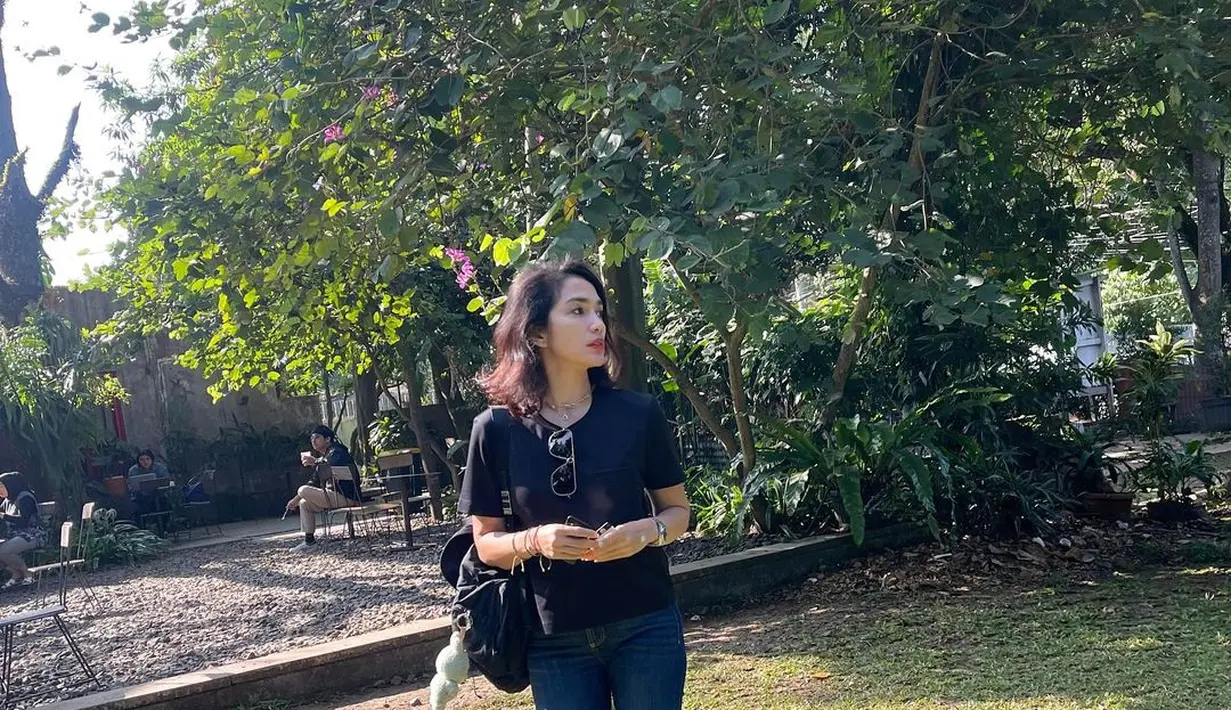 Penampilan kasual awet muda, Ussy pakai kaus hitam lengan pendek dengan celana jeans, sneakers putih, dan backpack yang juga berwarna hitam. [Foto: Instagram/ussypratama]