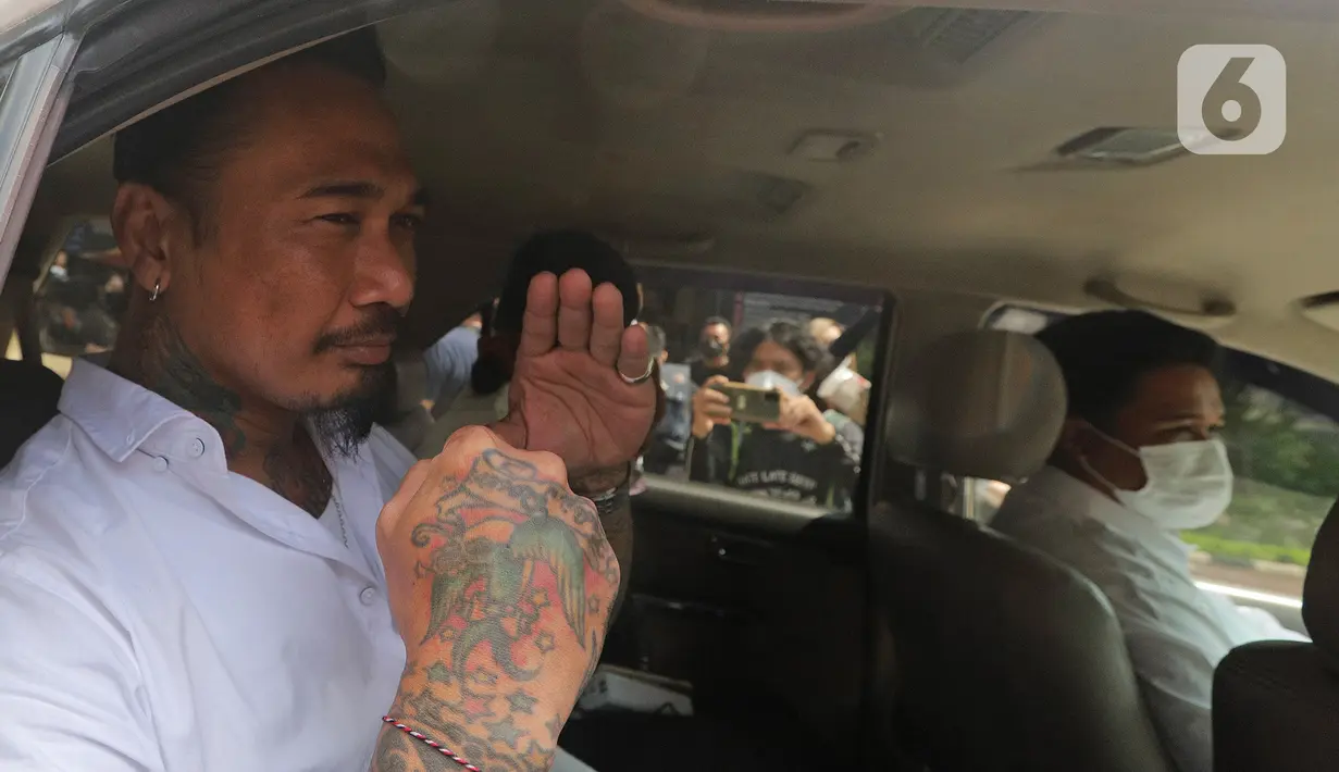 Musikus I Gede Ary Astina alias Jerinx memasuki mobil saat akan meninggalkan Polda Metro Jaya, Jakarta, Sabtu (14/8/2021). Polisi memulangkan Jerinx yang sudah menjadi tersangka kasus pengancaman usai bermediasi dengan pengiat sosial Adam Deni. (Liputan6.com/Herman Zakharia)