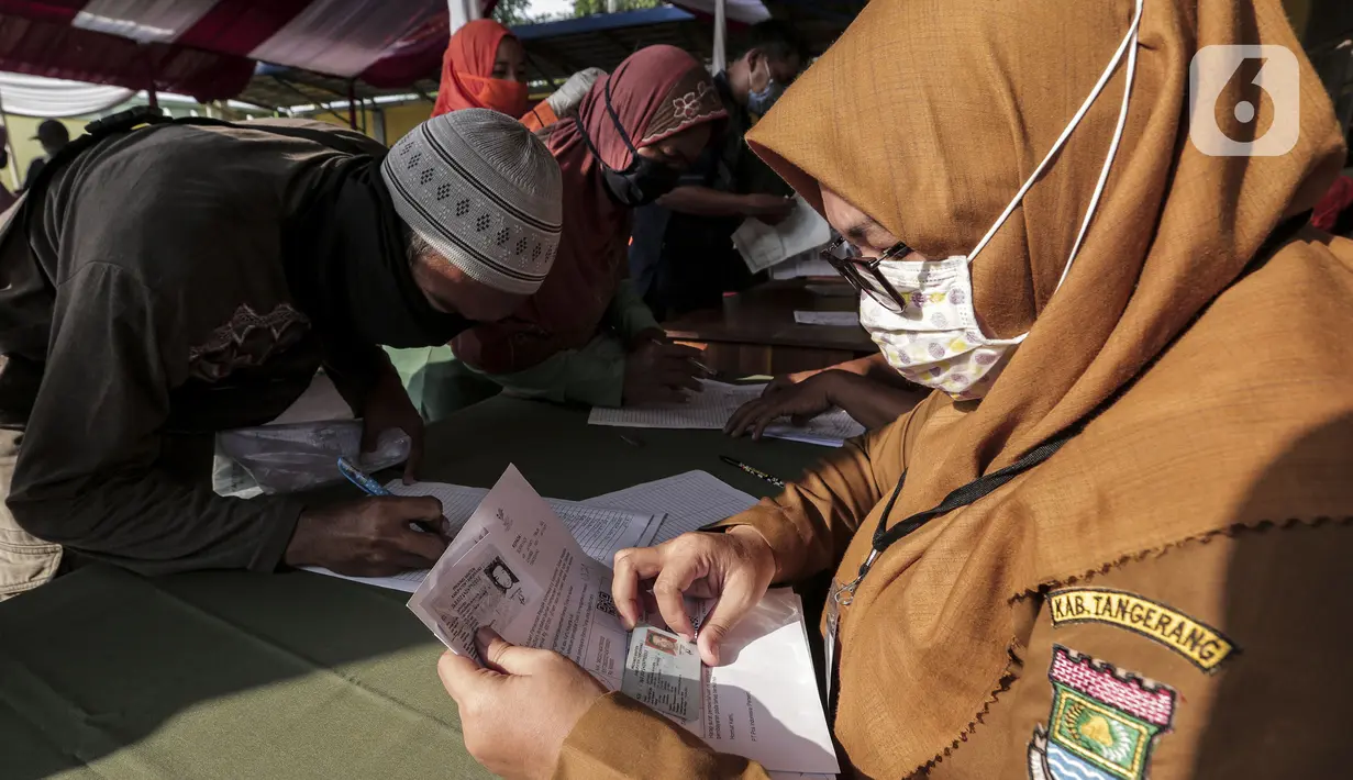 Petugas melayani warga yang antre menerima Bantuan Sosial Tunai (BST) di Desa Cikande, Kecamatan Jayanti, Kabupaten Tangerang, Banten, Selasa (23/6/2020). Bantuan tersebut merupakan salah satu program jaring pengaman sosial terkait pandemi virus corona COVID-19. (Liputan6.com/Johan Tallo)