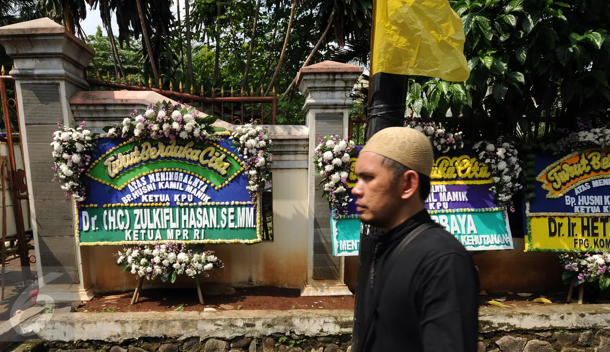 Pelayat melintasi karangan bunga duka cita wafatnya Ketua KPU Husni Kamil Manik di Kompleks KPU, Jakarta, Jumat (8/7). Sejumlah pejabat tinggi negara hadir melayat jenazah Husni Kamil Manik yang wafat, Kamis (7/7). (Liputan6.com/Helmi Fithriansyah)
