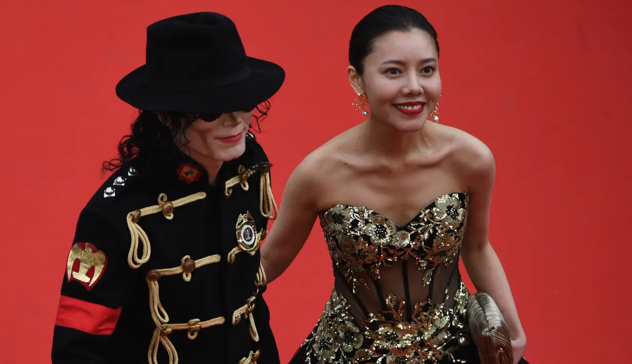 Seorang pria berpenampilan Michael Jackson didampingi wanita cantik menghadiri pemutaran film Solo: A Star Wars Story di Festival Film Cannes, Prancis, Selasa (15/5). Belum diketahui dengan pasti siapa pria tersebut. (AFP/Antonin THUILLIER)
