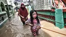 Seorang anak dan wanita berpegangan pada tali saat menyusuri banjir yang merendam permukiman di Kebon Pala, Jakarta, Senin (8/2/2021). Hujan deras yang mengguyur Ibu Kota dan Bogor menyebabkan permukiman di Kebon Pala terendam banjir sejak Minggu (7/2/2021) sore. (merdeka.com/Iqbal S. Nugroho)