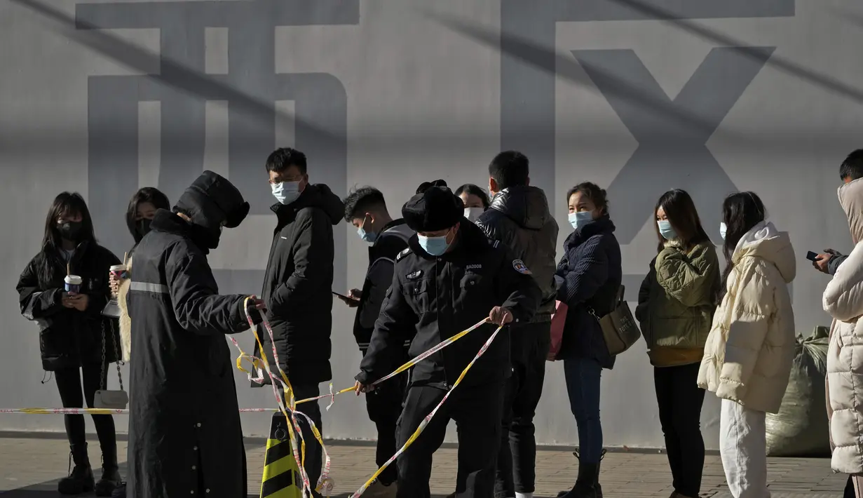 Petugas memasang garis barikade ketika orang-orang mengantre untuk mendapatkan tes COVID-19 di fasilitas pengujian virus corona seluler di Beijing (16/1/2022). Beijing telah melaporkan infeksi omicron lokal pertamanya, beberapa minggu sebelum Olimpiade Musim Dingin akan dimulai. (AP Photo/Andy Wong)
