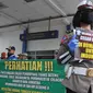 Seorang Polwan Direktorat Lalu Lintas Polda Jawa Tengah menunjukkan poster Cegah Covid-19 saat sterilisasi puluhan angkutan bus yang masuk di Terminal Bawen, Jumat (27/3/2020). (Liputan6.com/Gholib)
