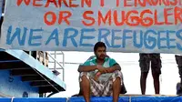 Seorang imigran Sri Lanka duduk di bawah spanduk yang menyatakan mereka pengungsi dan bukan teroris atau korban penyelundupan manusia di Tanjungpinang, Kepri. (Antara).