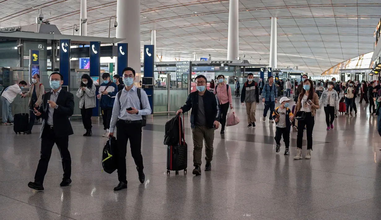 Orang-orang tiba di Bandara Internasional Ibu Kota Beijing untuk melakukan perjalanan menjelang liburan "Golden Week" pada 30 September 2020. Gelombang liburan melanda China yang warganya merayakan libur panjang, yang dikenal dengan Golden Week. (NICOLAS ASFOURI / AFP)