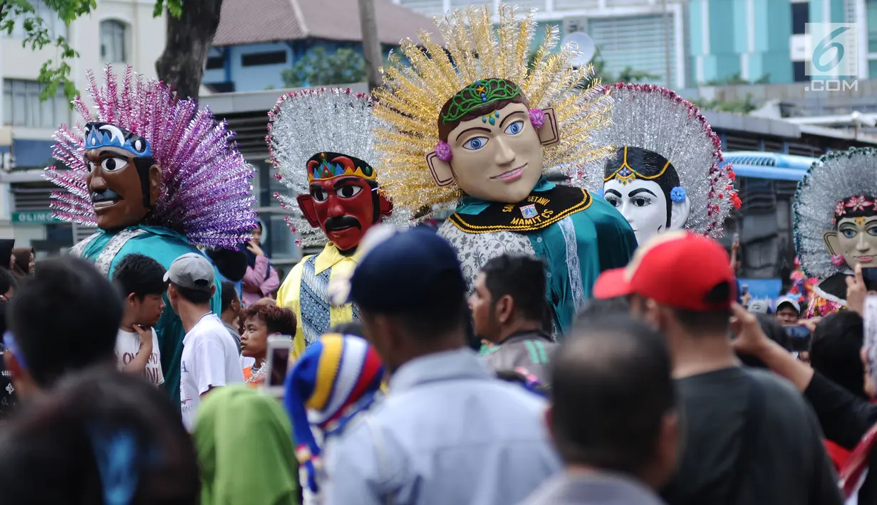 Atraksi ondel-ondel beraksi diantara kerumunan warga di Jalan Gajah Mada, Jakarta, Minggu (4/3). Beragam atraksi budaya yang ada di Indonesia ditampilkan dalam karnaval perayaan Cap Go Meh 2018 di kawasan Glodok Jakarta. (Liputan6.com/Helmi Fithriansyah)