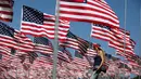 Seorang wanita berjalan diantara 3.000 bendera AS pada peringatan 15 tahun bagi para korban 11 September 2001 di Malibu, California, (11/09). Pengibaran bendera AS dilakukan sejak matahari terbit sampai terbenam. (REUTERS/Lucy Nicholso)