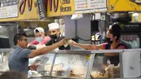 Uang dipertukarkan di stan makanan sementara para pekerja mengenakan masker di dalam Grand Central Market, Los Angeles pada Rabu (13/7/2022). Los Angeles County mungkin memberlakukan mandat masker pada 29 Juli 2022 jika jumlah COVID-19 terus meningkat. (AP Photo/Marcio Jose Sanchez)