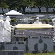 Petugas kesehatan menggunakan alat pelindung diri (APD) membawa peti jenazah korban Covid-19 (AP/Arsip)