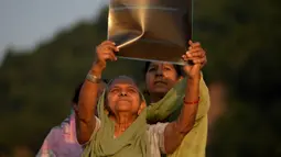 Perempuan menyaksikan Gerhana Matahari sebagian melalui film sinar-X di tepi Sungai Tawi, Jammu, India, Selasa (25/10/2022). Peristiwa Gerhana Matahari terakhir pada tahun 2022 terlihat dari sebagian besar Eropa, serta Afrika Utara, Timur Tengah, dan Asia Barat. (AP Photo/Channi Anand)