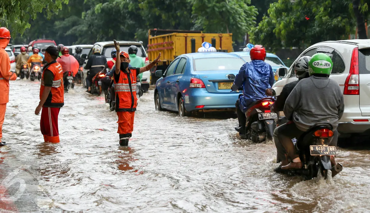 Petugas PPSU Srengseng Sawah melakukan pengaturan kendaraan yang melintas di jalan Lenteng agung, Jakarta, (12/2). Akibat Hujan deras,  jalan Lenteng Agung tepat di depan Universitas Pancasila  tergenang banjir hingga 50 cm. (Liputan6.com/Yoppy Renato)