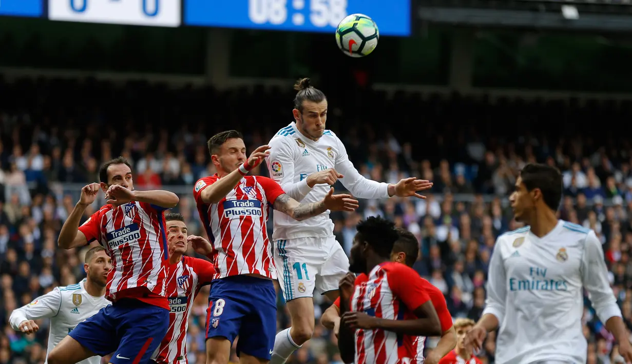 Pemain depan Real Madrid Gareth Bale berebut bola dengan pemain Atletico Madrid saat pertandingan La Liga Spanyol di stadion Santiago Bernabeu di Madrid (8/4). Real Madrid harus puas ditahan imbang 1-1 oleh Atletico Madrid. (AP Photo / Francisco Seco)