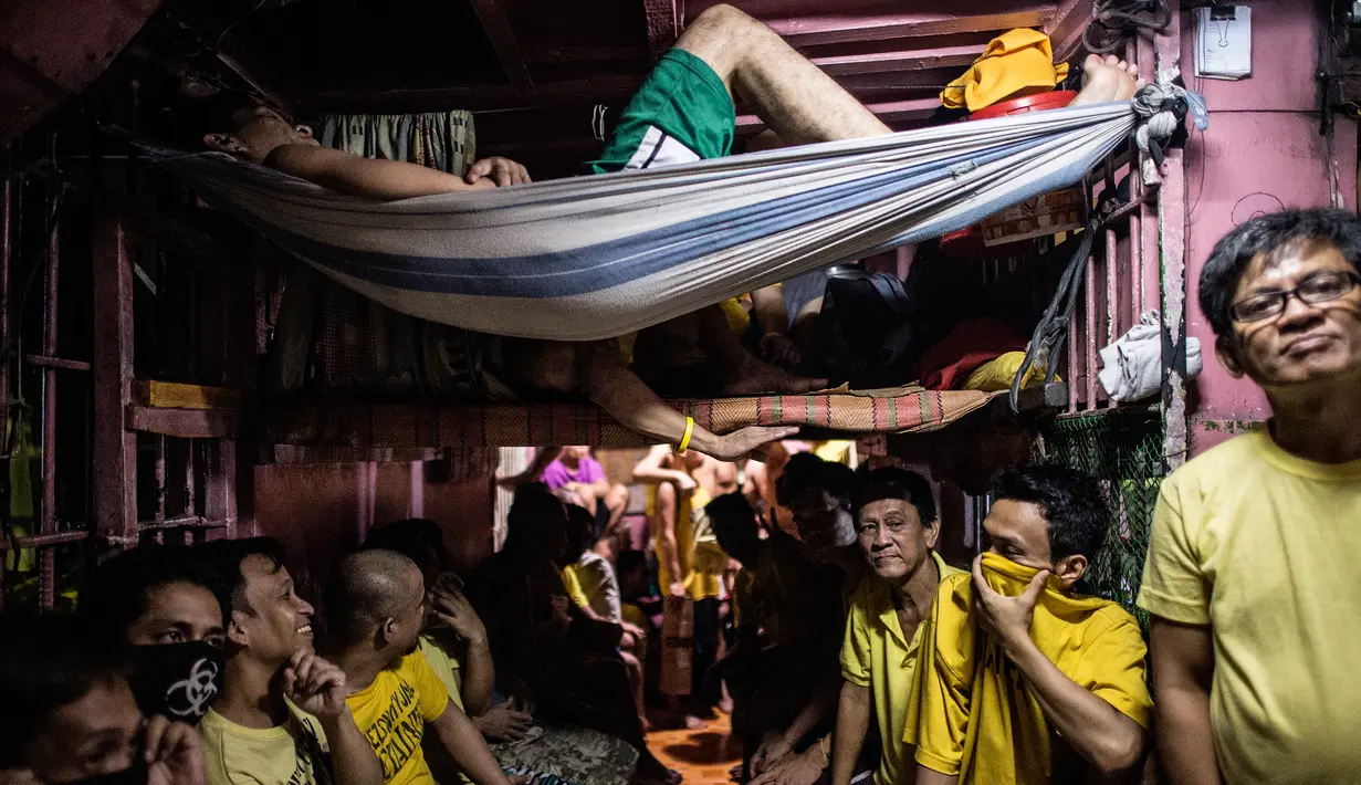 Seorang narapidana menggunakan selimut lusuhnya menjadi tempat tidur gantung di penjara Quezon City di Manila, Filipina, 18 Juli 2016. Para tahanan di penjara Quezon City juga menggunakan satu ruangan yang difungsikan serba guna. (Noel Celis/AFP)