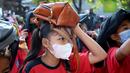 Anak-anak sekolah menggunakan tas mereka untuk melindungi diri saat latihan gempa dan tsunami di Tanjung Benoa, Kabupaten Badung, Bali, 24 Mei 2022. (SONY TUMBELAKA/AFP)