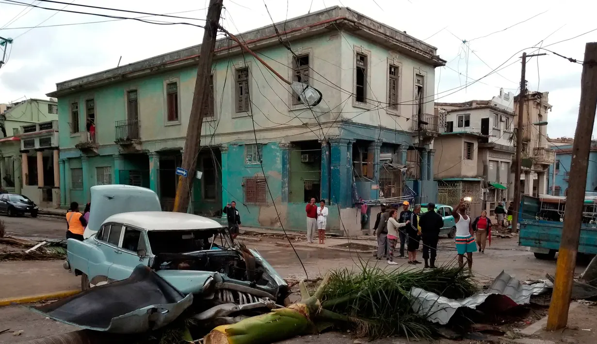 Sebuah mobil rusak tertimpa pohon setelah badai tornado menghantam Regla, Kuba (28/1). Hantaman tornado mengakibatkan rumah-rumah hancur berantakan, mobil bergelimpangan hingga pepohonan tumbang. (AP Photo/Ramon Espinosa)