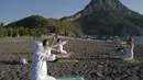 Orang-orang berlatih yoga di pantai di Adrasan, barat Antalya, Turki (24/9/2021). Orang-orang menikmati cuaca hangat di wilayah Mediterania saat salju pertama menyelimuti pegunungan tinggi di timur laut Turki. (AP Photo/Burhan Ozbilici)