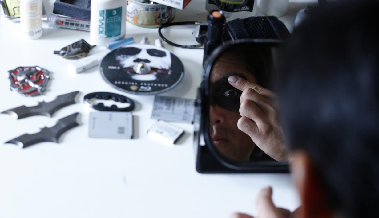 Manusia kelelawar kota Chiba tersebut tengah merias wajahnya sebelum berkeliling dengan motornya bernama Chibatpod, Jepang, (31/8/14). (REUTERS/Yuya Shino)