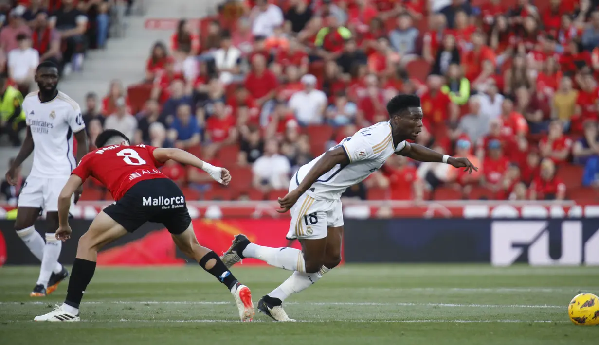 Pemain Real Madrid, Aurelien Tchouameni, melewati pemain Real Mallorca, Manu Morlanes, pada laga Liga Spanyol di Stadion Son Moix, Sabtu (13/4/2024). (AP Photo/Francisco Ubilla)