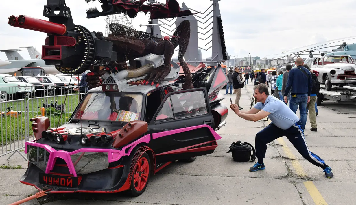 Seorang pengunjung mengambil gambar dari sebuah mobil yang dihias selama hari pembukaan festival mobil retro OldCarLand di Kiev (27/4). Pameran kendaraan jadul ini digelar dari 27 April hingga Mei, 1, 2018. (AFP Photo/Sergei Supinsky)