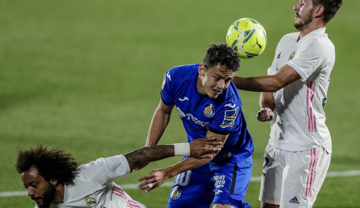 Pemain Real Madrid, Victor Chust, duel udara dengan pemain  Getafe, Enes Unal, pada laga Liga Spanyol di Stadion Alfonso Perez, Senin (19/4/2021). Kedua tim bermain imbang 0-0. (AP Photo/Manu Fernandez)