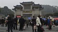 Orang-orang terlihat di luar pemakaman Biandanshan pada hari pertama Tahun Baru Imlek di Wuhan, provinsi Hubei, China pada Jumat (12/2/2021). Penduduk Wuhan, China bersiap menggelar perayaan Imlek yang setahun lalu tak bisa mereka rayakan akibat pandemi Covid-19. (Hector RETAMAL / AFP)