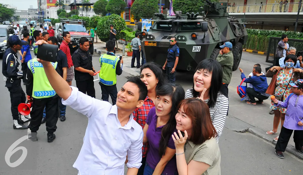 Sejumlah warga berfoto bersama di dekat panser Anoa milik TNI yang berjaga di di LTC Glodok, Jakarta, Jumat (4/11). Panser tersebut mulai terparkir sekitar pukul 00.30 WIB untuk mengantisipasi peristiwa yang tidak diinginkan. (Liputan6.com/Angga Yuniar)