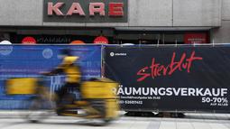 Seorang tukang pos melewati toko yang tutup di pusat kota Munich, Jerman, Selasa (23/3/2021). Jerman memperpanjang tindakan pengunciannya sebulan lagi. (AP Photo/Matthias Schrader)