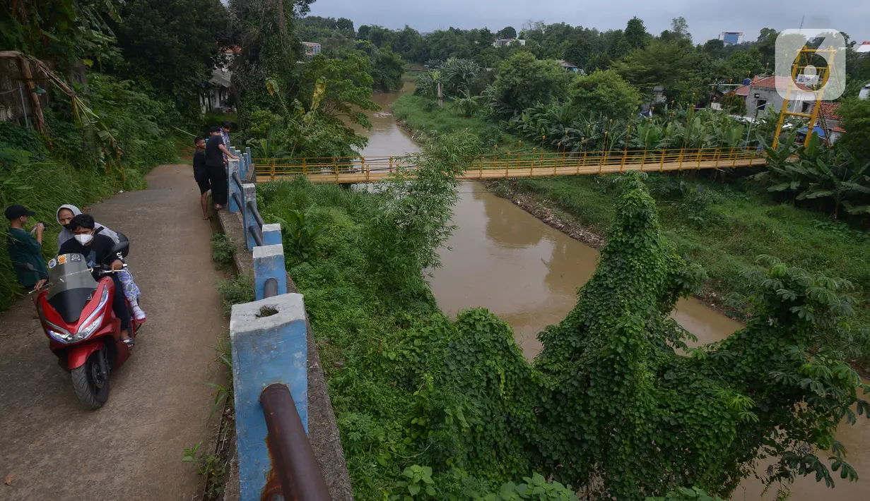 Kendaraan melintas dekat jembatan gantung Kuning yang menghubungkan Pasar Minggu Poltangan ke Cililitan Condet, Jakarta, Selasa (28/12/2021). Jembatan gantung Kuning tersebut merupakan jalan umum dan akses jalan warga yang ingin berlalu-lalang. (merdeka.com/Imam Buhori)