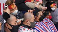 Pemilik usaha kecil dicukur rambutnya saat rapat umum menentang aturan jaga jarak dari pemerintah dekat Majelis Nasional di Seoul, Korea Selatan, 25 Januari 2022. Korea Selatan mencatat lebih dari 8.000 infeksi COVID-19 baru untuk pertama kalinya. (AP Photo/Ahn Young-joon)