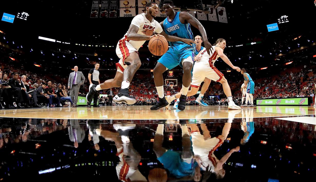 Pebasket Miami Heat, James Johnson (kiri) mencoba melewati adangan pebasket Hornets, Johnny O'Bryant III #8  pada laga NBA pre-season di American Airlines Arena, Miami, (9/10/2017). Miami Heat menang 109-106. (Mike Ehrmann/Getty Images/AFP)