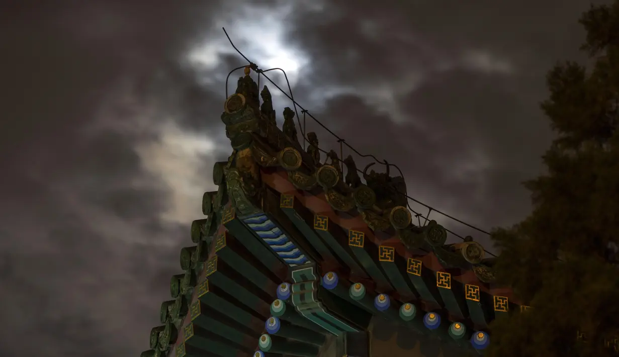 Dekorasi atap yang menggambarkan mitos binatang suci terlihat siluet di dekat gerhana bulan penumbra yang terhalang oleh awan di Beijing, China pada Sabtu dini hari (6/5/2023). (AP Photo/Ng Han Guan)