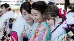 Tiga wanita berpakaian Kimono swafoto selama upacara perayaan Coming of Age Day atau Hari Kedewasaan di Tokyo  (14/1). Upacara kedewasaan sudah digelar di Jepang untuk pangeran muda sejak 714 Masehi. (AP Photo/Koji Sasahara)