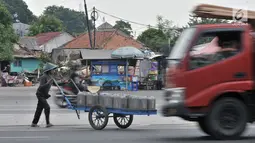 Pedagang air bersih saat dengan hati-hati menyeberangi jalan di persimpangan Terminal Pulo Gadung, Jakarta, Rabu (5/9). Menurut warga setempat, kecelakaan hampir setiap hari terjadi di persimpangan ini. (Merdeka.com/Iqbal Nugroho)