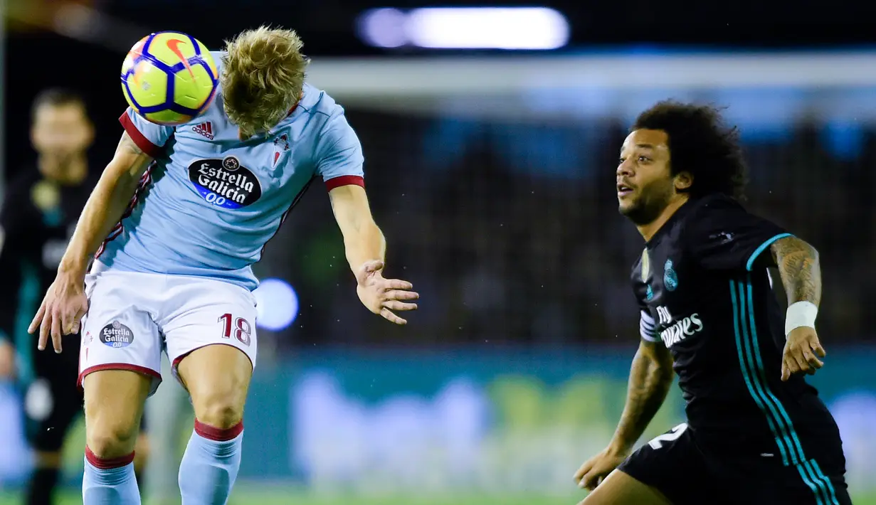 Gelandang Celta Vigo Daniel Wass dan bek Real Madrid, Marcelo berebut bola pada pertandingan pekan ke-18 La Liga kontra Celta Vigo di Estadio de Balaidos, Minggu (7/1). Real Madrid ditahan imbang 2-2 saat berkunjung ke markas Celta Vigo (MIGUEL RIOPA/AFP)