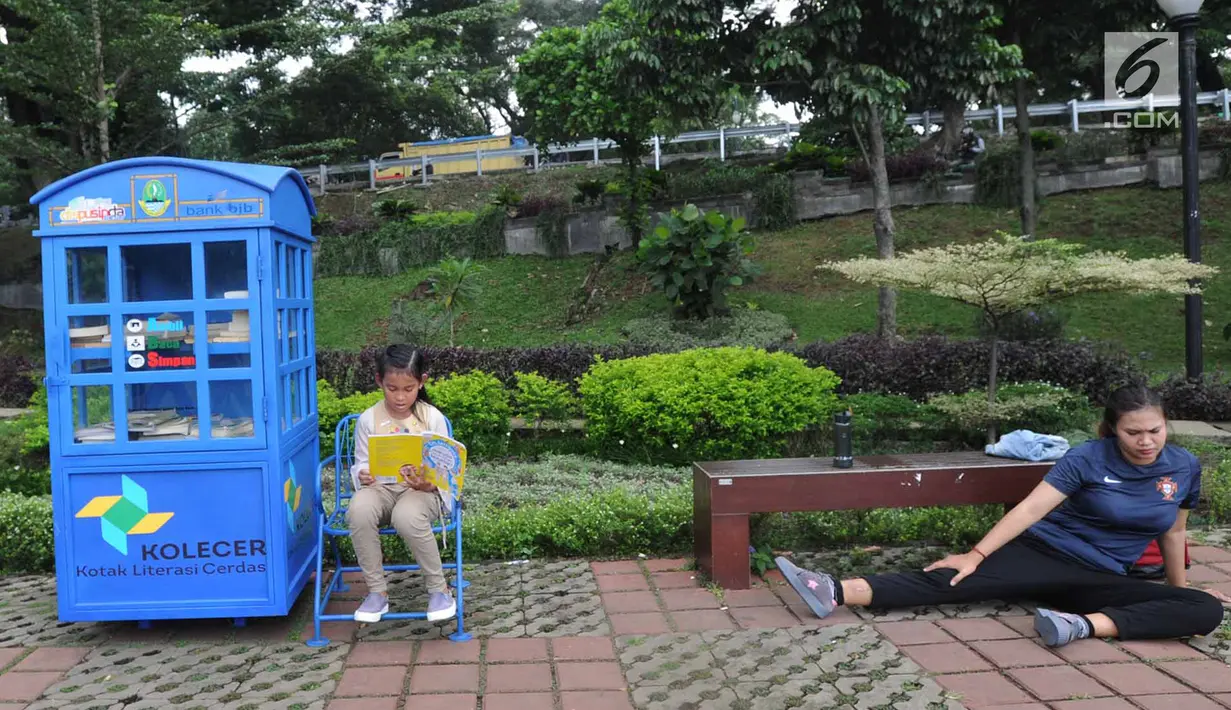Warga berolahraga dekat anak yang sedang membaca buku di layanan Kotak Literasi Cerdas (Kolecer) di Taman Sempur, Bogor, Jawa Barat, Kamis (20/12). Kolecer adalah perpustakaan jalanan gratis. (Merdeka.com/Arie Basuki)